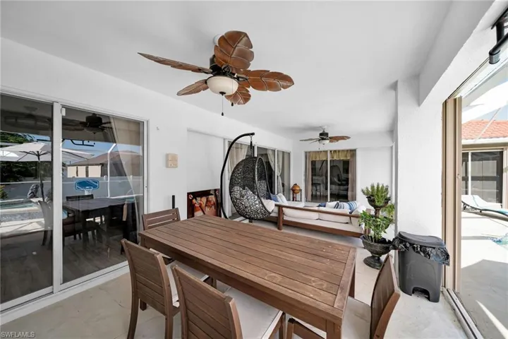 Sunroom with outdoor dining space, a ceiling fan, and a patio