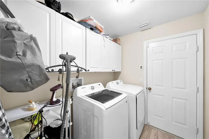 Washroom featuring cabinet space, light wood-style floors, and washing machine and dryer