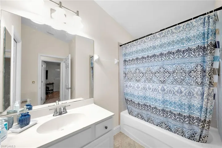 Full bath featuring shower / tub combo with curtain, vanity, and light tile patterned flooring