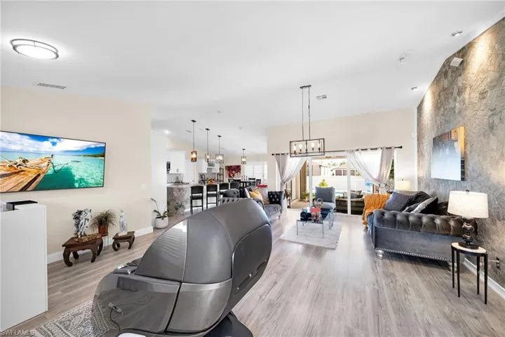 Living room featuring lofted ceiling, light wood-style flooring, and a chandelier