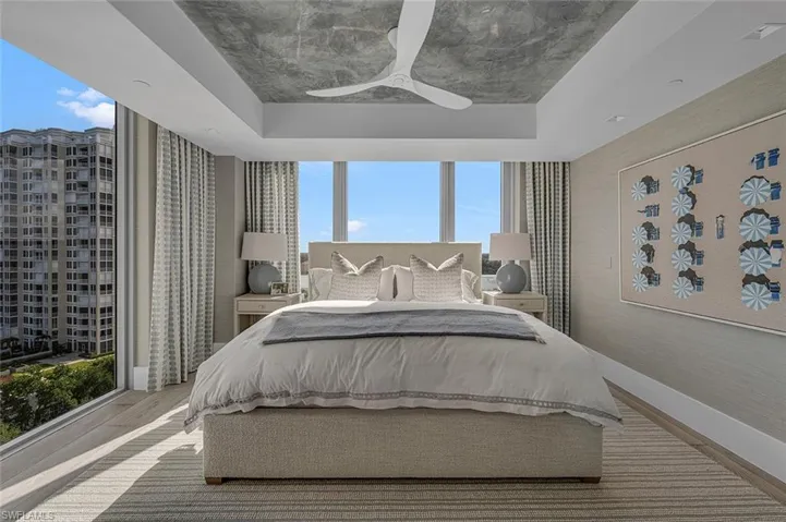 Bedroom with ceiling fan, a raised ceiling, and wood-type flooring