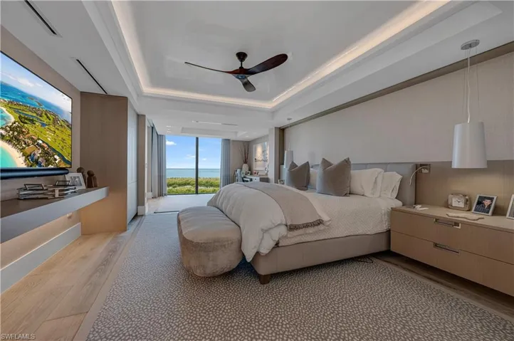 Bedroom with a tray ceiling, access to exterior, ceiling fan, and light hardwood / wood-style floors