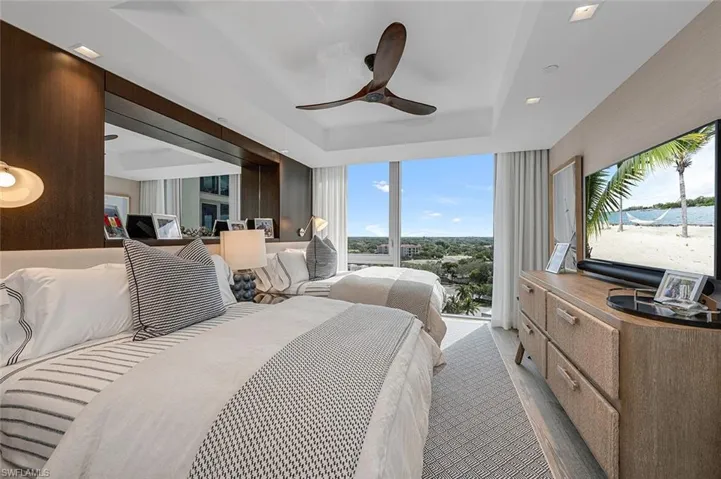 Bedroom featuring ceiling fan, a raised ceiling, access to outside, and light colored carpet