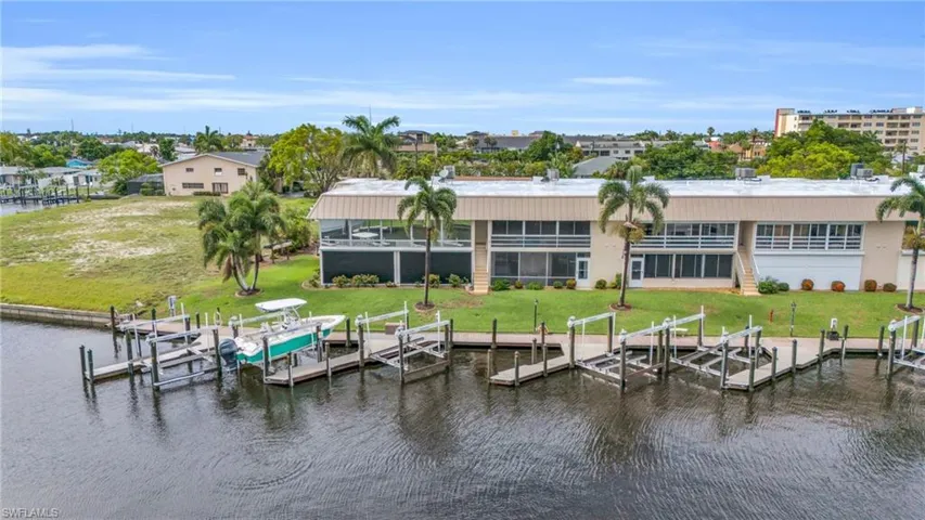 Back of property with a water view and a lawn