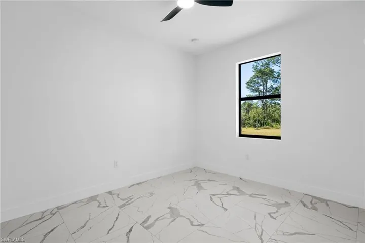 Unfurnished room with baseboards, light marble finish floors, and ceiling fan