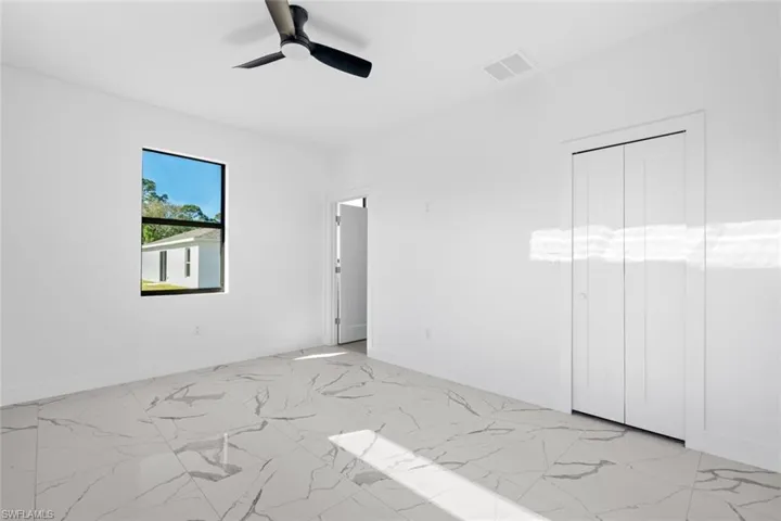 Unfurnished bedroom with light marble finish flooring, baseboards, and a ceiling fan