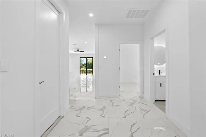 Corridor featuring light marble finish flooring, baseboards, recessed lighting, and a sink