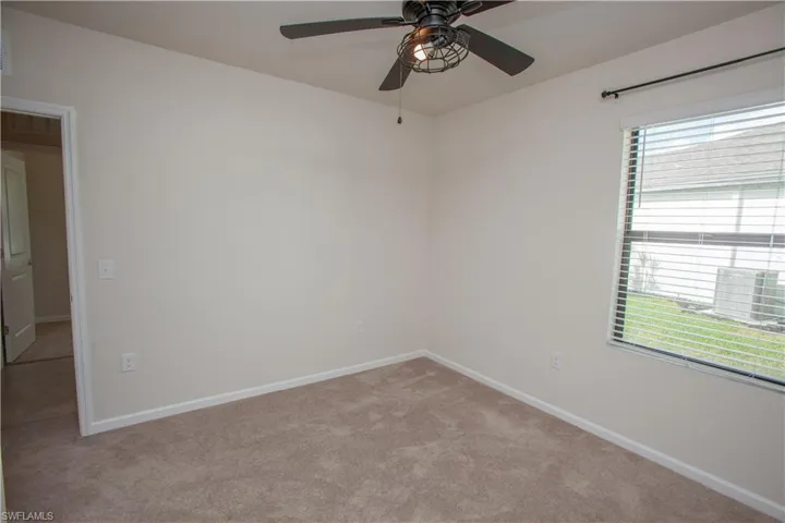 Unfurnished room featuring a ceiling fan and light colored carpet