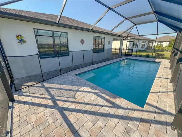 Outdoor pool featuring glass enclosure and a patio area