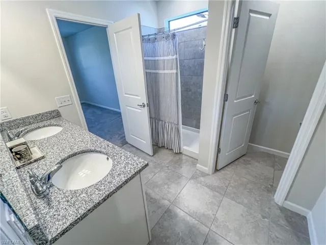 Full bath featuring a shower stall, double vanity, and tile patterned flooring