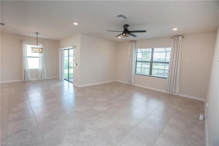 Unfurnished room featuring plenty of natural light, recessed lighting, light tile patterned floors, a ceiling fan, and a chandelier