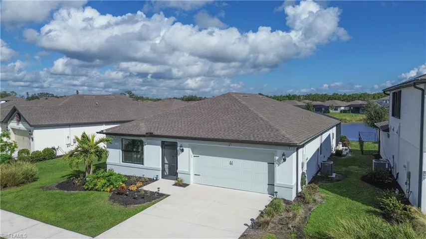 View of front of property with an attached garage, a shingled roof, a front lawn, and concrete driveway