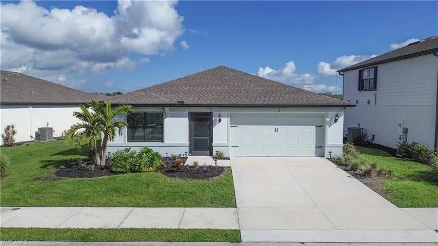 Ranch-style home with stucco siding, an attached garage, driveway, central AC unit, and a front lawn