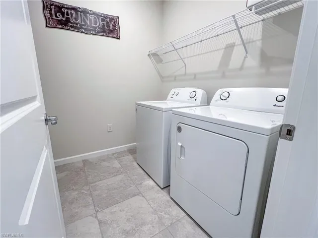 Laundry room featuring washing machine and dryer and baseboards