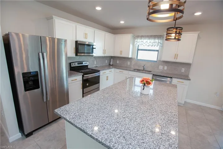 Kitchen with appliances with stainless steel finishes, white cabinets, backsplash, and recessed lighting