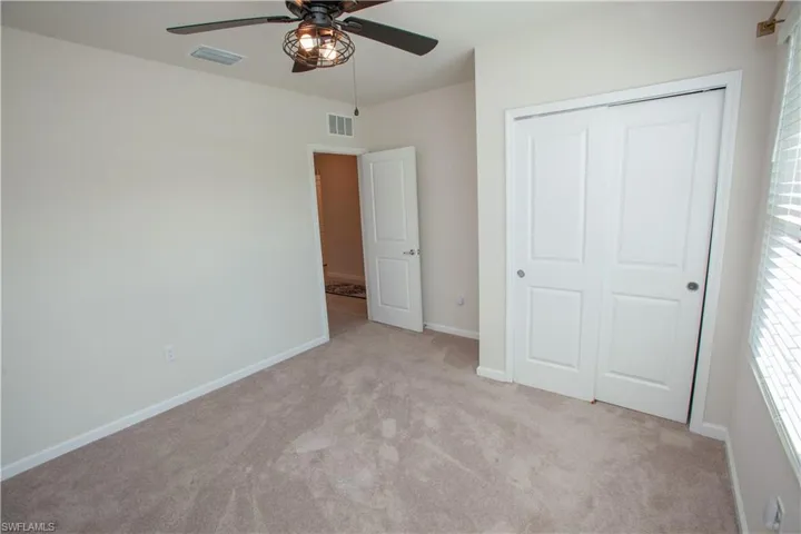 Unfurnished bedroom featuring light carpet, a closet, and ceiling fan