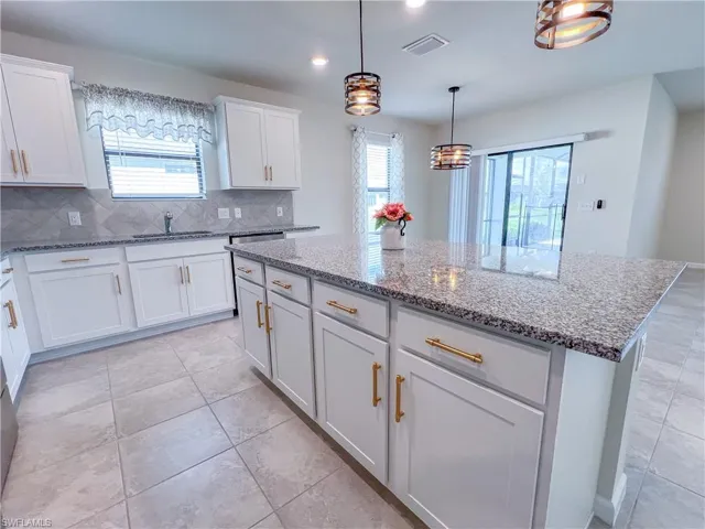 Kitchen with decorative backsplash, light stone counters, plenty of natural light, a center island, and recessed lighting