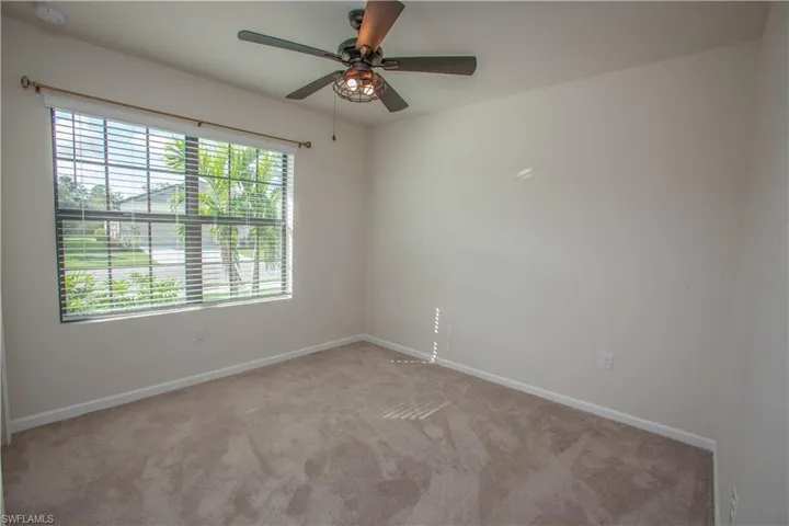 Carpeted spare room with ceiling fan and a smoke detector