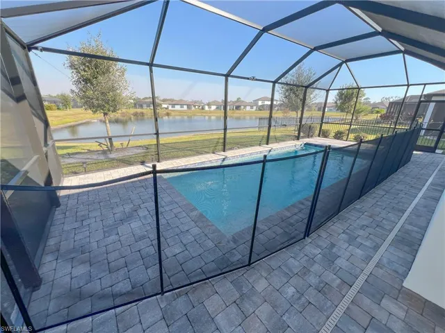 Outdoor pool featuring glass enclosure, a water view, and a patio area