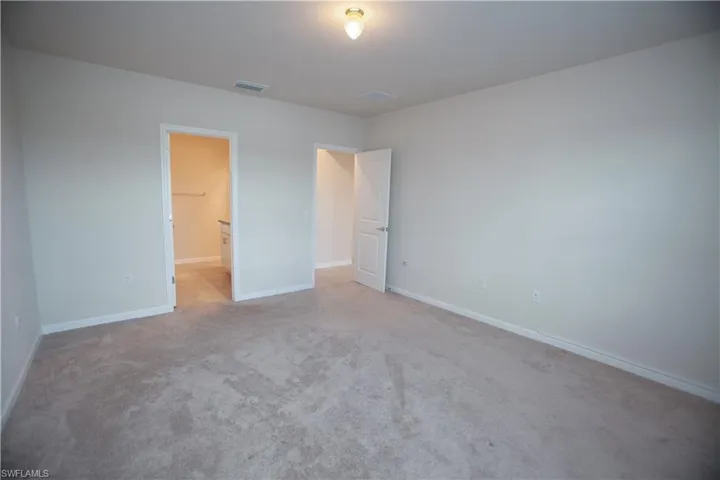 Unfurnished bedroom with light colored carpet and a spacious closet