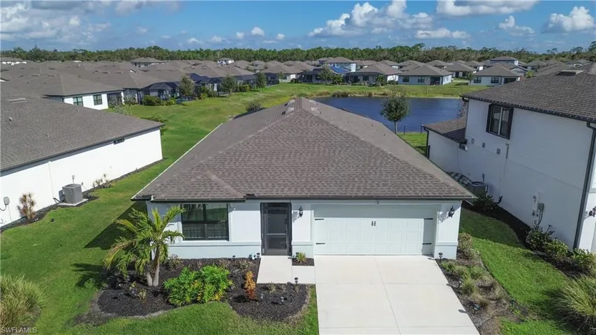 View of front of property with central AC unit, an attached garage, a front lawn, a residential view, and driveway