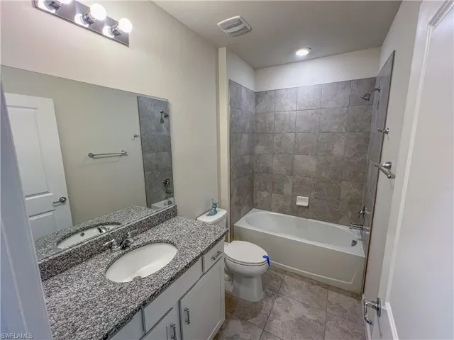 Bathroom with vanity, bathtub / shower combination, and tile patterned flooring