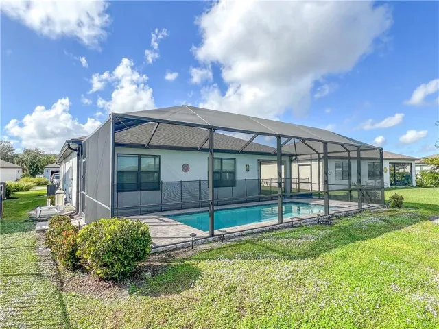 Rear view of house with a lawn, a lanai, and an outdoor pool