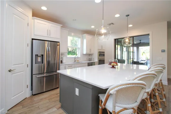 Kitchen featuring appliances with stainless steel finishes, light wood-type flooring, sink, pendant lighting, and white cabinetry