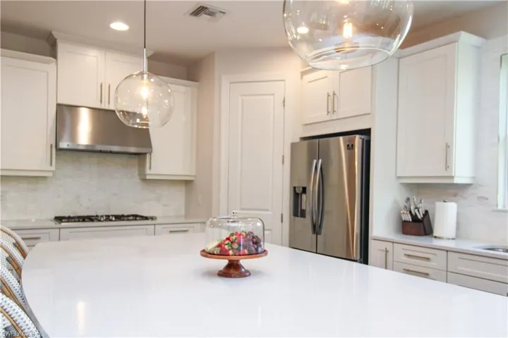 Kitchen featuring white cabinetry, stainless steel appliances, and tasteful backsplash