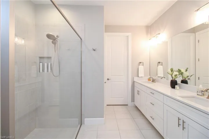 Bathroom featuring tile patterned floors, vanity, and tiled shower