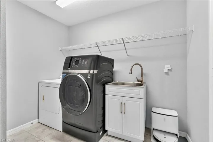 Laundry area featuring washing machine and clothes dryer and light tile patterned floors