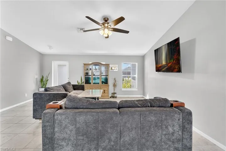 Living area featuring a ceiling fan, lofted ceiling, and light tile patterned floors