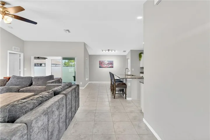 Living area featuring a ceiling fan, light tile patterned flooring, and vaulted ceiling