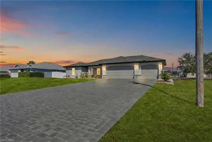 Prairie-style home with a front yard, a garage, decorative driveway, and stone siding