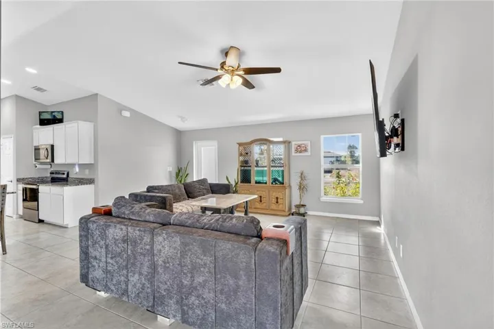 Living area with a ceiling fan, light tile patterned flooring, lofted ceiling, and recessed lighting