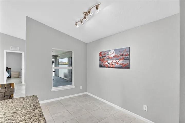 Unfurnished dining area featuring lofted ceiling and light tile patterned floors