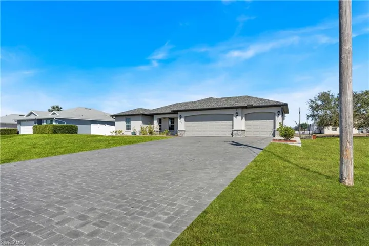 Prairie-style home featuring an attached garage, a front lawn, decorative driveway, and stone siding