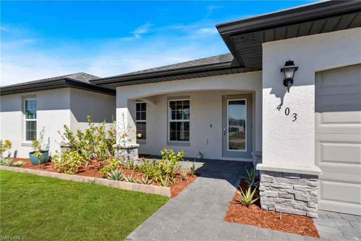 Entrance to property with a porch, stucco siding, and a yard