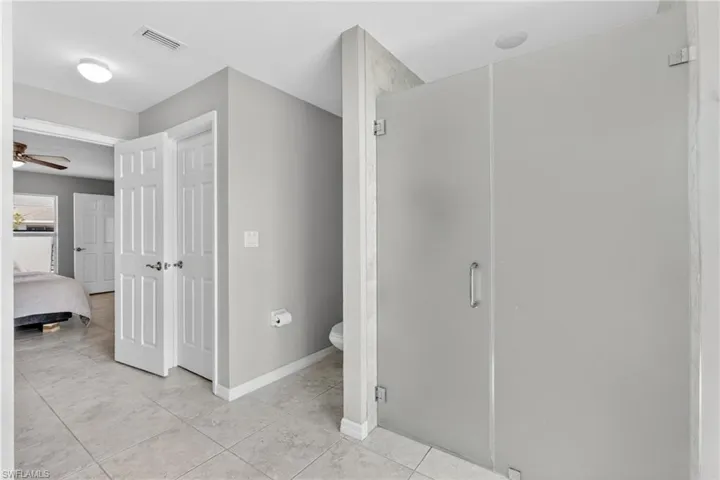 Ensuite bathroom featuring a stall shower, ceiling fan, and light tile patterned floors