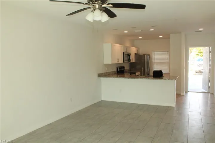 Kitchen featuring dark stone counters, a peninsula, stainless steel appliances, ceiling fan, and recessed lighting