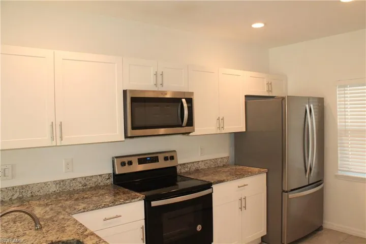 Kitchen featuring stainless steel appliances, white cabinets, dark stone counters, and recessed lighting