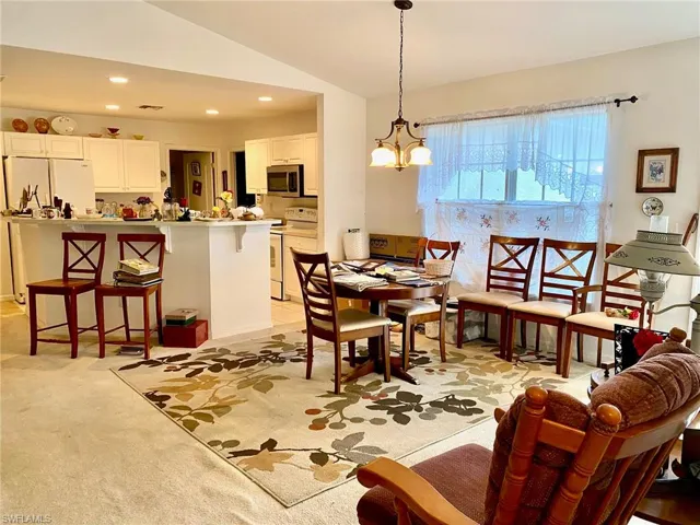 Carpeted dining space with an inviting chandelier and lofted ceiling