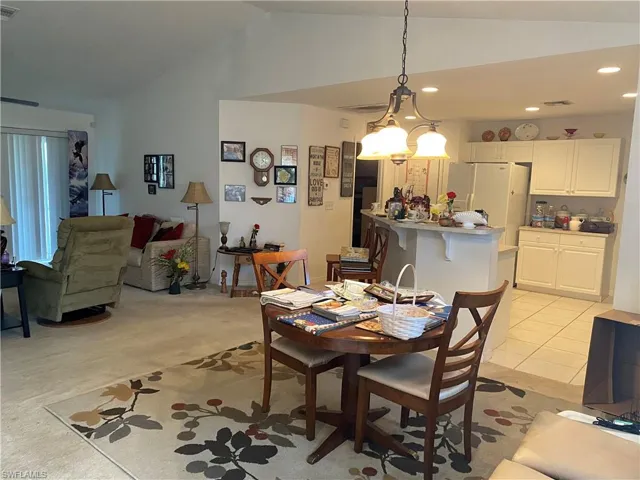 Carpeted dining room featuring lofted ceiling and a chandelier