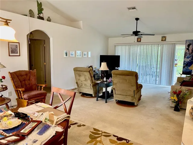 Living room featuring carpet, ceiling fan, and vaulted ceiling