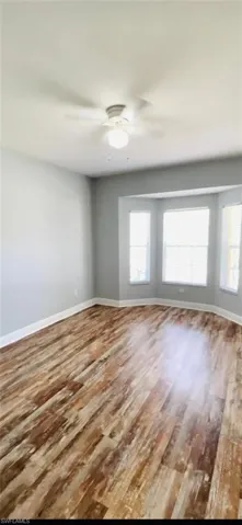 Room featuring wood-finish flooring, a bay window with multi-pane glazing, and a ceiling-mounted light fixture
