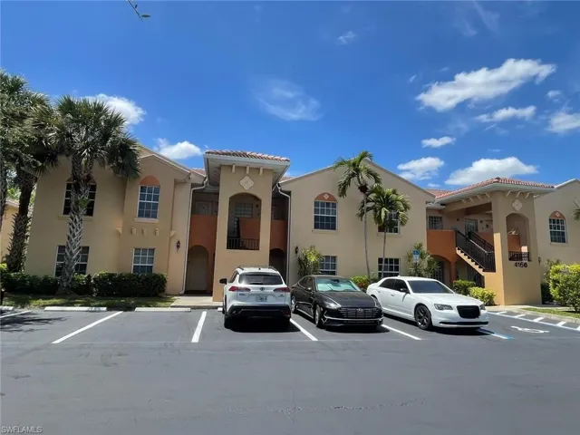 Stucco exterior featuring dual-pitched tile roofing, arched entryways, integrated staircases, and mature palm landscaping