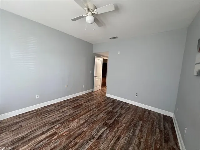 Room featuring wood-finish flooring, neutral wall paint, and a ceiling-mounted light fixture with a fan