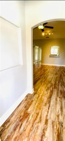 Arched entryway featuring wood-finish flooring, recessed wall niche, and an integrated wall-mounted shelf