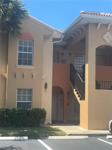 Stucco exterior featuring arched architectural detailing, glass block windows, decorative wall corbels, and a metal staircase railing