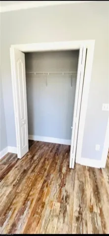 Closet featuring bi-fold doors, white interior casing, and built-in wire shelving, set against wood-finish flooring